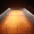 Outdoor clay tennis court lit with linear LED lights mounted along the fence